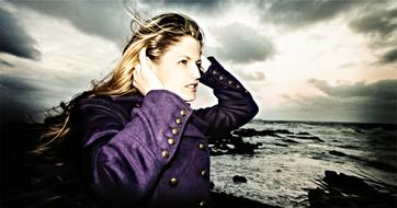 Portrait of a posing, blonde woman in violet jacket, on the beach
