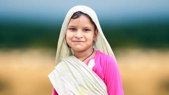 joyful girl in traditional costume on blurred background