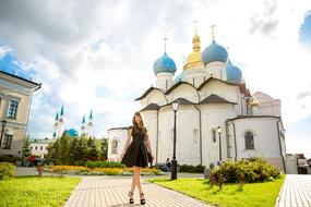 Girl in dress, near the beautiful and colorful monastery, among the plants