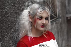bright blonde with colorful makeup near the wall