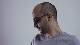 Profile portrait of the man, with the beard and short hair, with the glasses, in grey t-shirt