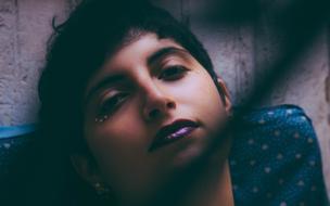 dark photo of a girl with short hair and bright makeup