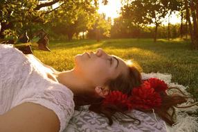 Bride, girl in Wedding dress lays on her back on lawn at sunset