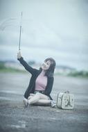 happy Beautiful asian Woman sits on pavement with transparent umbrella