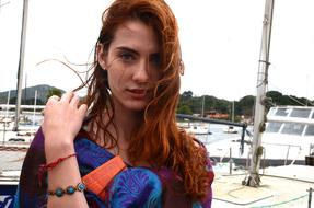 Portrait of the beautiful woman with ginger hair, with bracelets, in the port