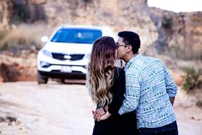 kiss girl with a guy on the background of the car