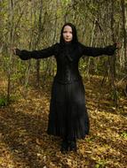 Woman, in the black dress, posing among the colorful and beautiful plants of the forest