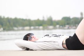 young Girl in dark glasses laying on her back outdoor