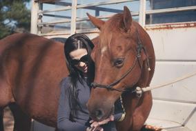 happy girl in sunglasses near brown horse