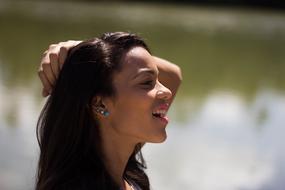Profile portrait of the woman with earrings, near the water with reflections