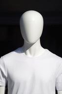 White mannequin in white clothing, in light, at black background