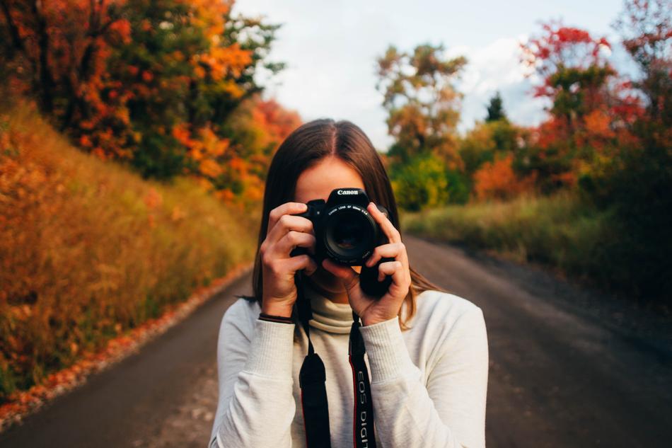 girl with a camera on the road on a blurred background