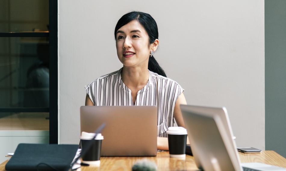 Portrait of a smiling woman, at the workplace with laptops and other stuff