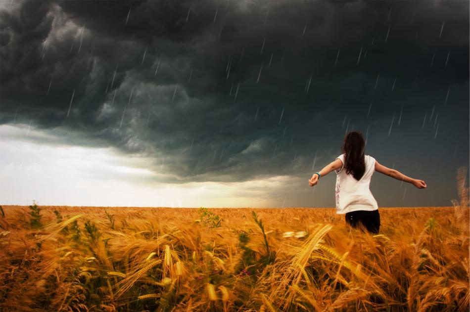 Landscape of the colorful field, with the woman with open hands, in raining storm
