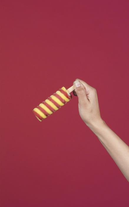 Person, holding beautiful, red and yellow, spiral ice cream, at red background