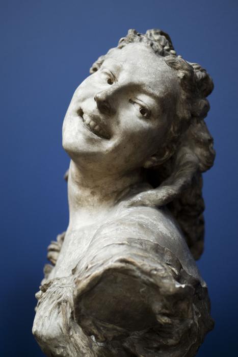 Sculpture of the smiling woman in light, at blue background