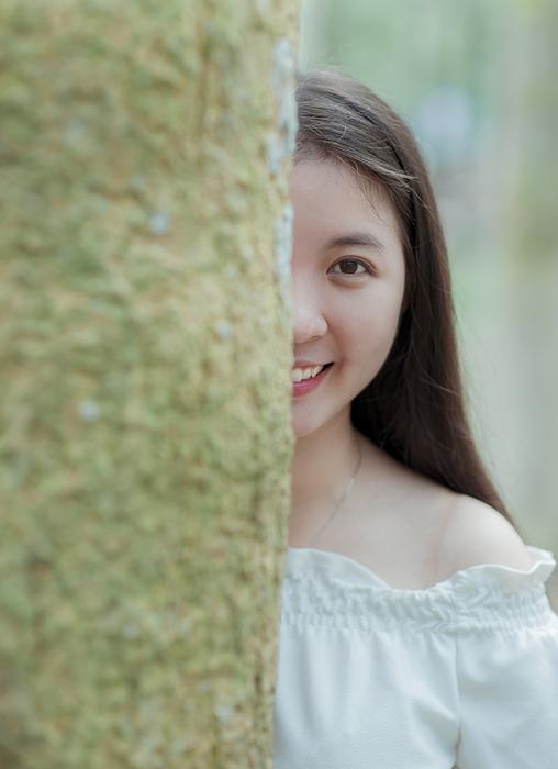 Smiling girl looking out of the tree in green moss