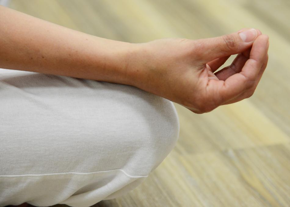 Close-up of the hand and leg of the meditating woman