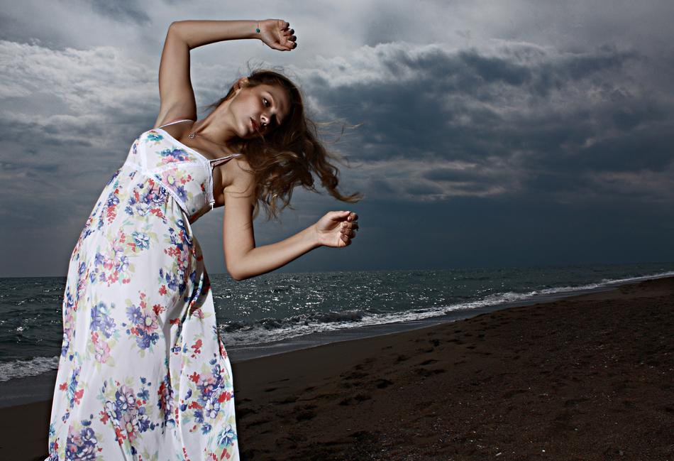 Woman in the colorful dress, on the dark landscape, under the clouds