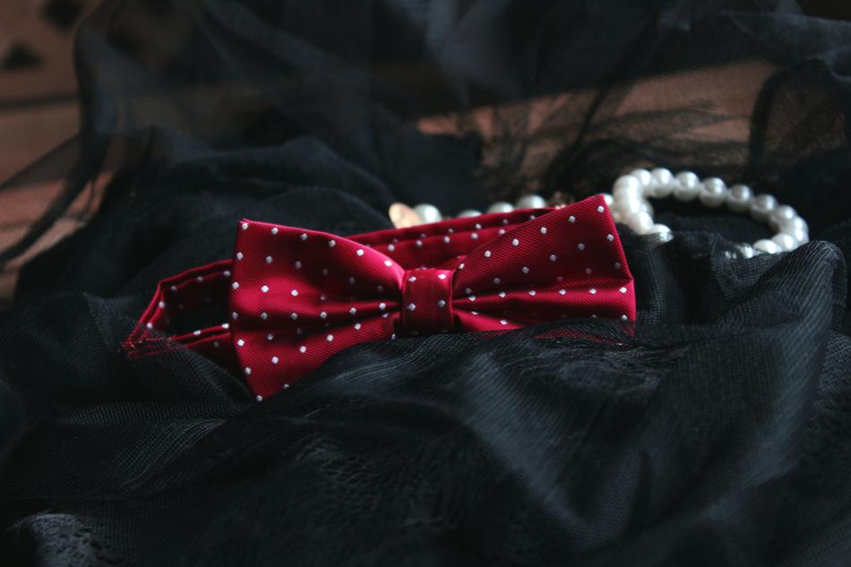 red bow tie next to pearl bracelet