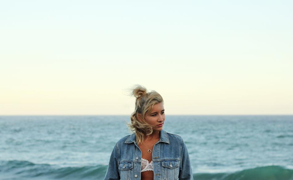 blonde in a denim jacket on the background of the sea