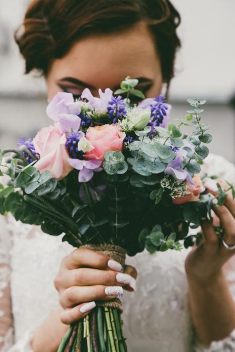 Bride with colorful bouquet in front of face