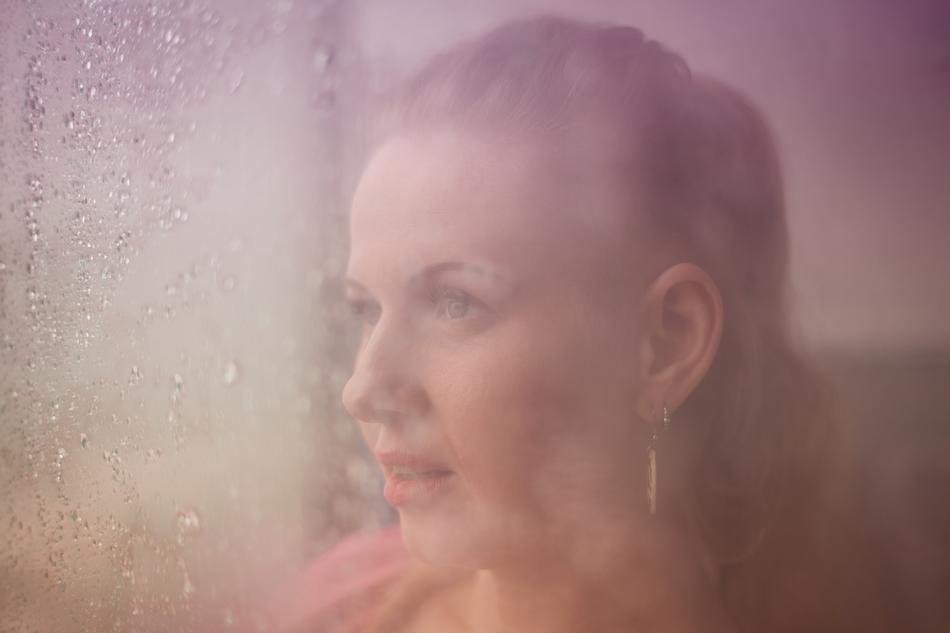 View of the portrait of the woman with earrings, behind the colorful window with water drops