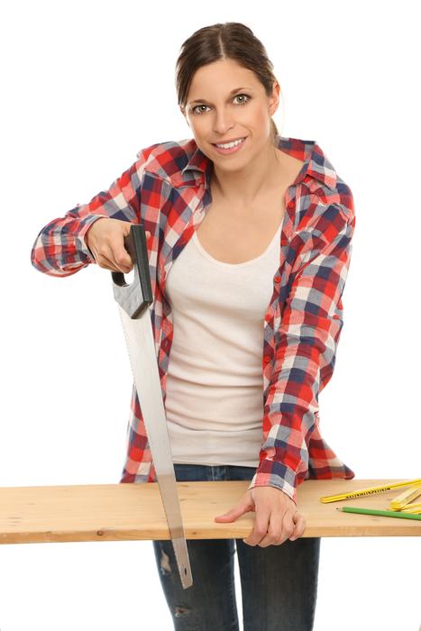 Smiling woman sawing block of wood, at white background