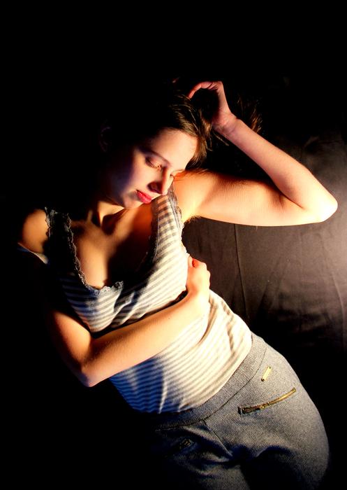 Woman with make-up and closed eyes, in light, among the darkness