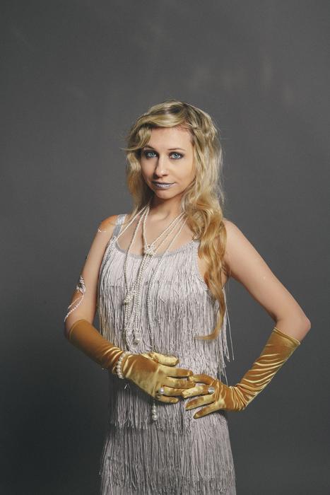 Blonde girl with make-up, gloves and pearls, at grey background