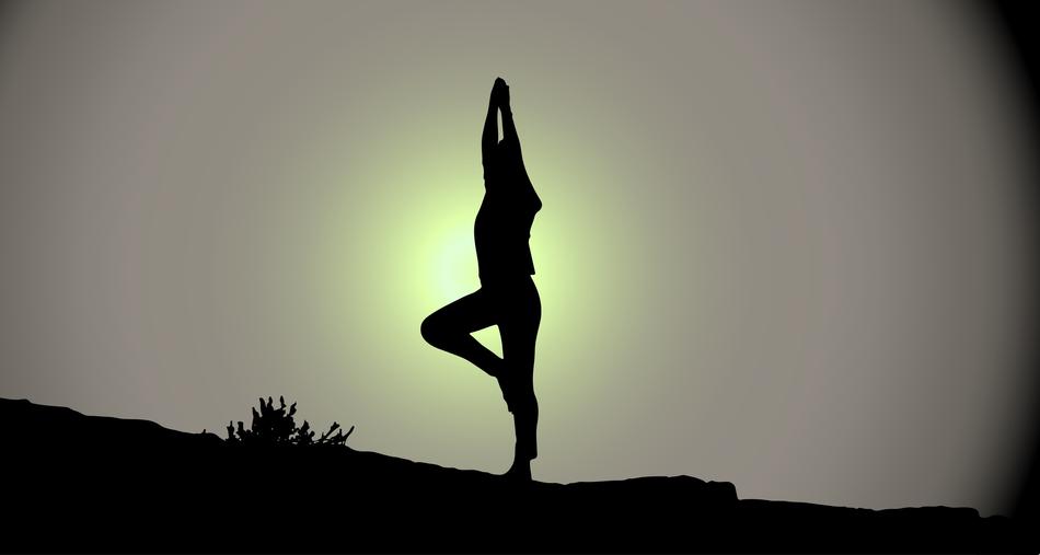 silhouettes of woman in yoga pose in dark twilight