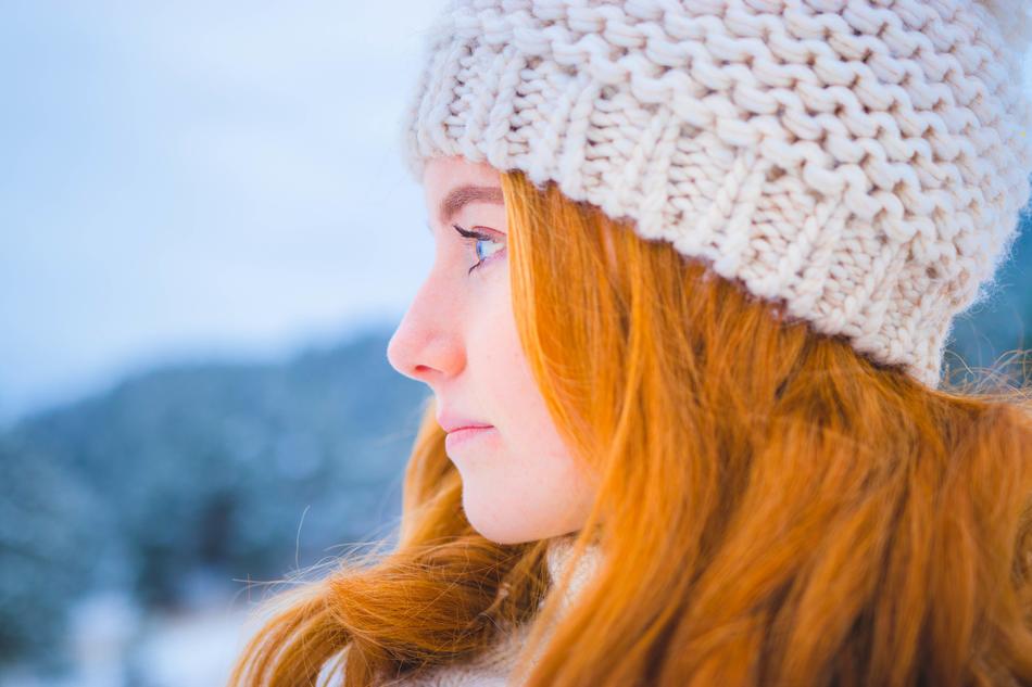 girl with red hair in a knitted hat on a blurred background