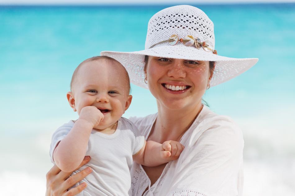 happy mom with baby on the beach on blurred background