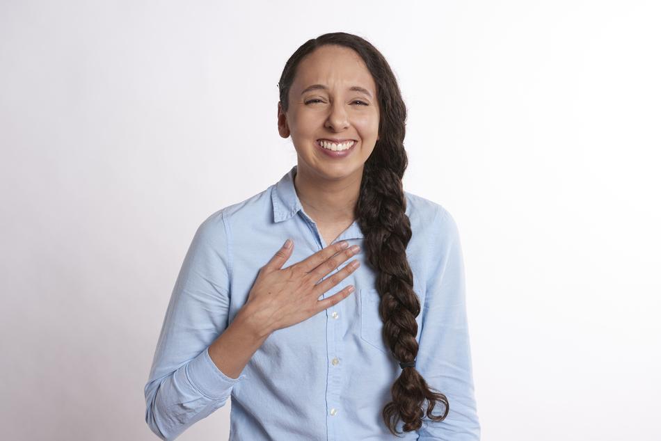 Flattered woman with hand on the shirt, at white background