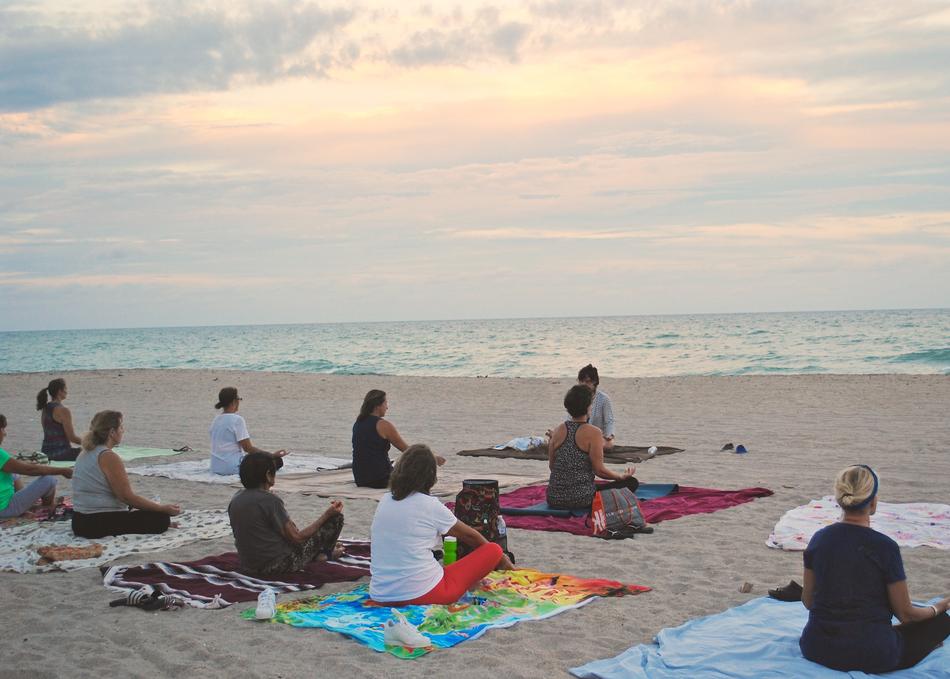 group of people doing yoga on the beach
