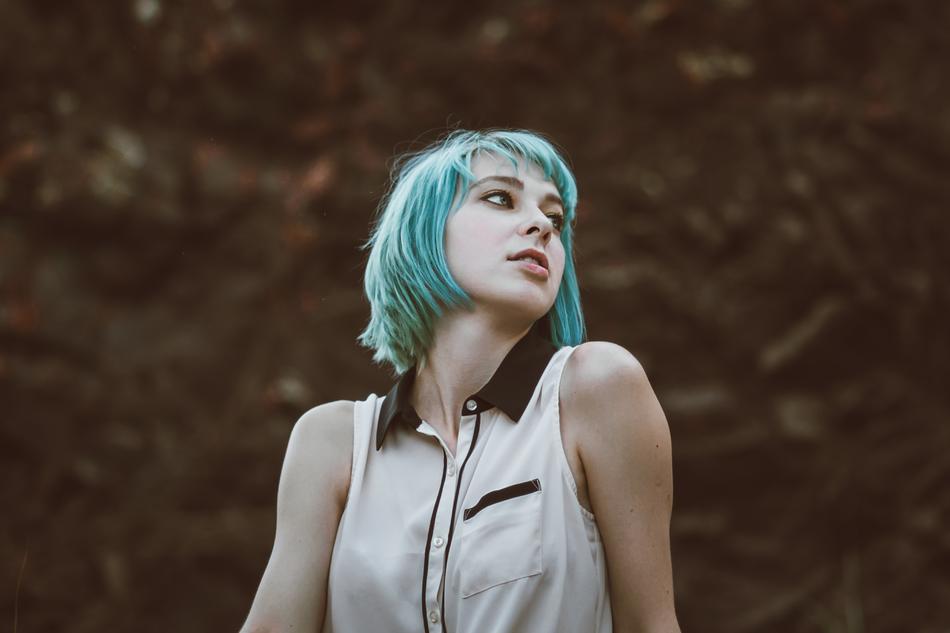 Girl with turquoise hair posing, at colorful, blurred background