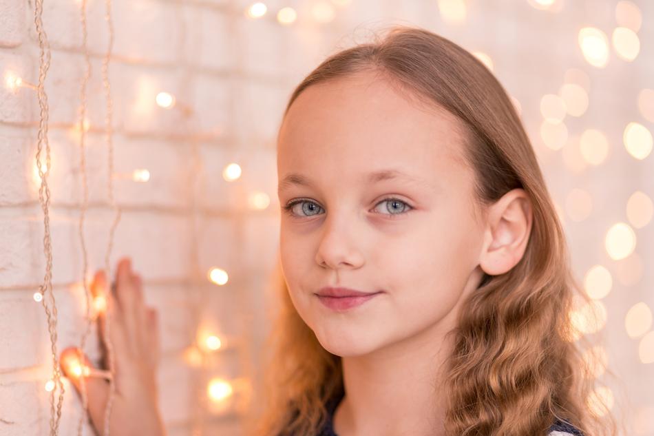 little girl posing near the wall with a garland