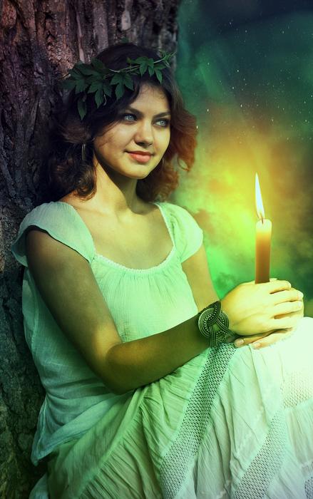 girl in a white dress with a candle by the tree