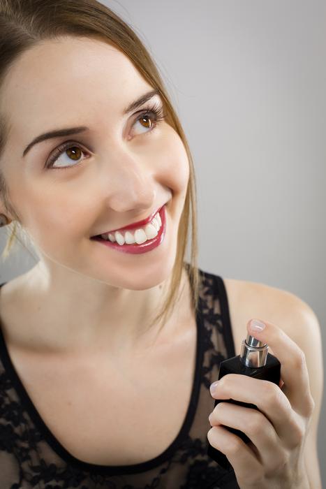 smiling girl with perfume in hand