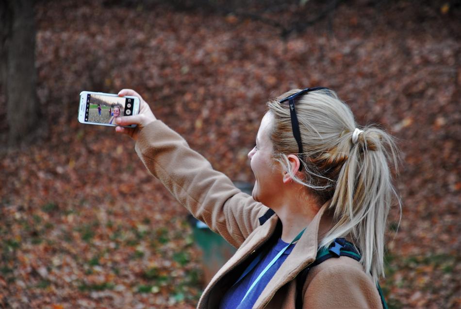 Smiling girl taking selfie among the colorful leaves