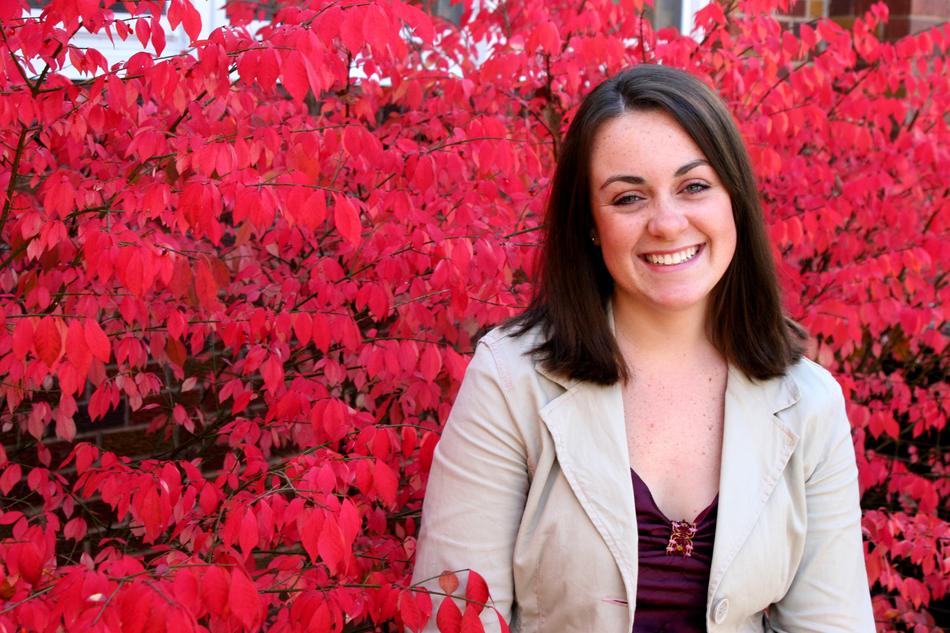 smiling brunette on the background of a bush with red leaves