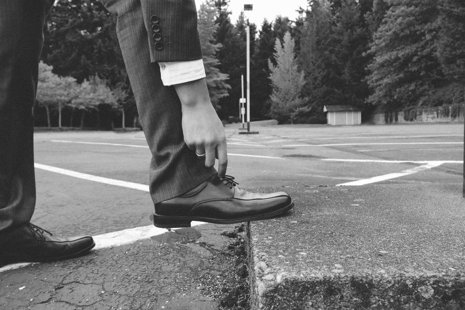 Black and white photo with close-up of the man's shoes on the ground, among the plants