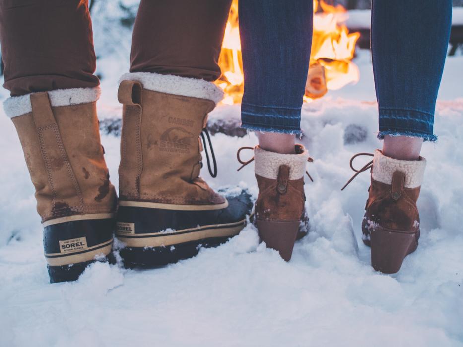Close-up of the people in snow footwear, near the fire, among the snow in the winter