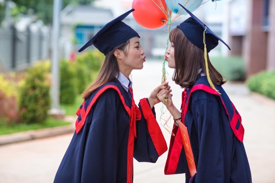 Two Asian girls with balloons, blowing a kiss on the Graduation