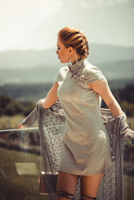 Posing woman in grey dress and with pigtail, on the beautiful landscape