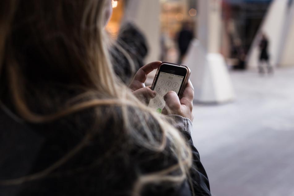 Back view of Woman with touchscreen phone in hands
