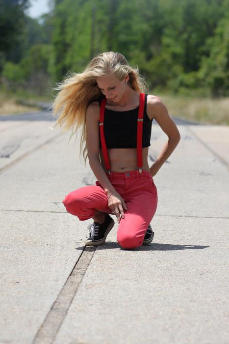Girl is sitting on the road on the landscape