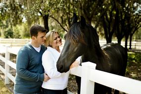 Hugging Couple and black Horse in corral