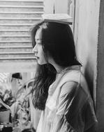 black and white asian girl with a book on her head by the window