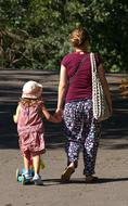 mom walks with her daughter on a scooter